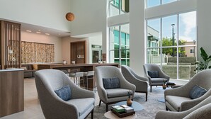 A modern lobby with grey armchairs, a reception desk, and large windows offering a view of the outside. - Element by Marriott Albuquerque Uptown (Albuquerque)