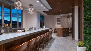 A modern kitchen with a long bar area, wooden accents, and a view of the mountains. - Element by Marriott Albuquerque Uptown (Albuquerque)
