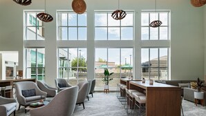 A spacious lounge area with multiple seating options, large windows, and a central wooden bar. - Element by Marriott Albuquerque Uptown (Albuquerque)