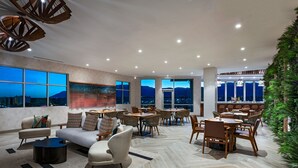 A spacious indoor area with multiple seating arrangements, large windows offering city views, and a modern ceiling design. - Element by Marriott Albuquerque Uptown (Albuquerque)