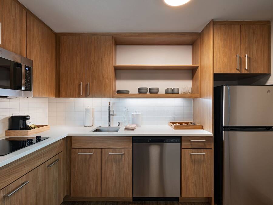 Una cocina moderna con armarios de madera, un refrigerador de acero inoxidable, un lavavajillas y un microondas.