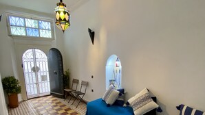 A spacious living area with a checkered floor, a blue sofa set, a patterned rug, and a decorative lantern. - Dar Coeur De Tanger (Tangier)