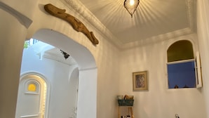 A room with a checkered floor, a weighing scale, a shelf with decorative items, and a window with a view. - Dar Coeur De Tanger (Tangier)