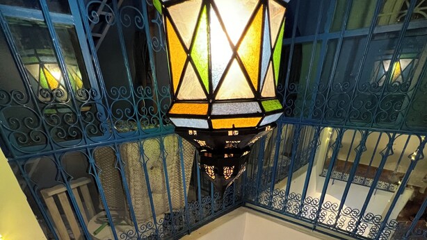 A multi-level interior with a checkered floor pattern, a staircase with blue railings, and a decorative lantern. - Dar Coeur De Tanger (Tangier)