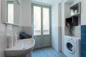 Un baño pequeño con lavamanos, lavadora y ventana con vistas al balcón.