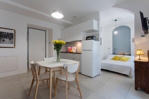 Un espacio habitable compacto con comedor, kitchenette y dormitorio.