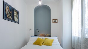 A bedroom with a bed, a nightstand, a lamp, and a framed picture on the wall. - Blu di San Salvario by Wonderful Italy (Turin)