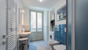 A modern bathroom with a sink, bidet, and washing machine. - Blu di San Salvario by Wonderful Italy (Turin)