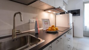 A modern kitchen with a stainless steel sink, a bowl of lemons, and a framed welcome sign. - Blu di San Salvario by Wonderful Italy (Turin)