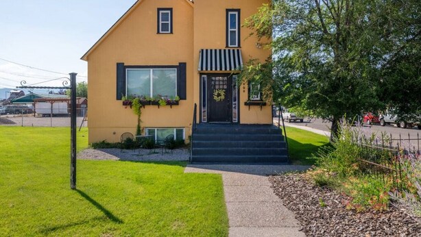 A yellow building with a black door, windows, and a small porch area.