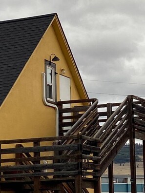 Un bâtiment jaune avec un toit noir, un escalier en bois et une vue sur une plage.