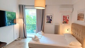Et hotelværelse med seng, fjernsyn, balkon og billedkunst på væggene.