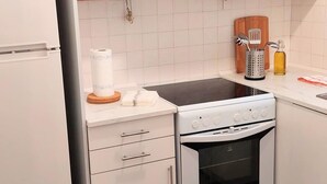 Et lille køkken med hvide skabe, en indbygget ovn og et komfur.