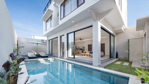 A modern house with a swimming pool, large glass doors leading to a living area, and a small garden.