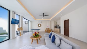 A modern living room with a grey sofa, a wooden coffee table, and a TV mounted on the wall.