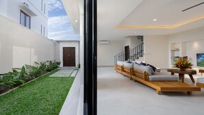A modern interior with a living area, a staircase, and a view of the outside.