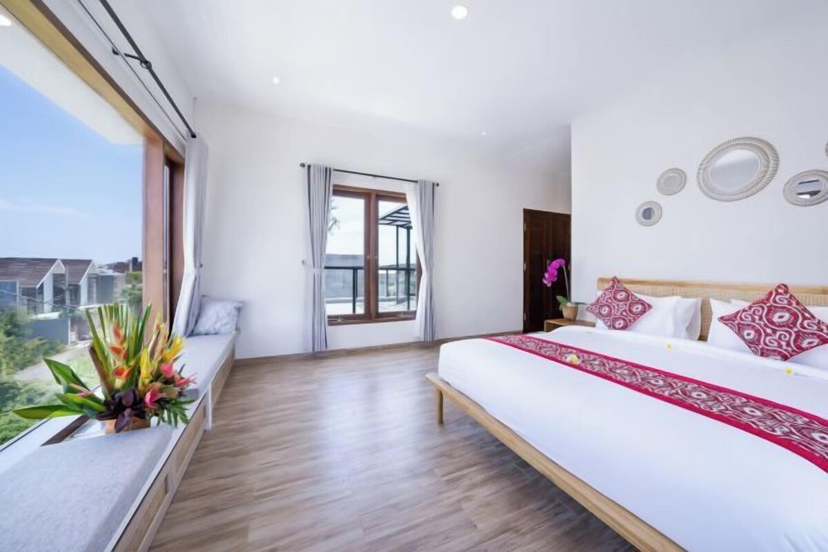 Un dormitorio con una cama grande, una ventana con cortinas y vistas al exterior.