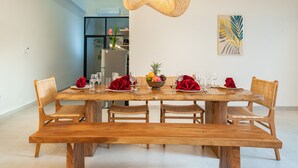 A dining area with a wooden table set for six, surrounded by wicker chairs.