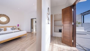 A modern bedroom with a wooden bed, a large mirror, and a view of the sky through an open door.