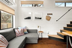En moderne stue med en grå modulsofa, trætrappe og et lille sofabord med en lampe.