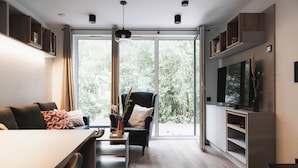 A modern living room with a sofa, armchair, dining table, and TV.