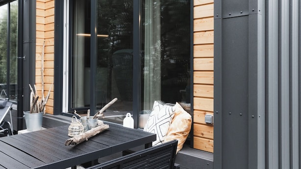 A modern outdoor seating area with a table and chairs, a metal bucket, and a wooden bench.