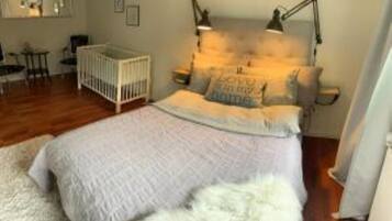 A bedroom with a bed, a crib, a nightstand, and a lamp.
