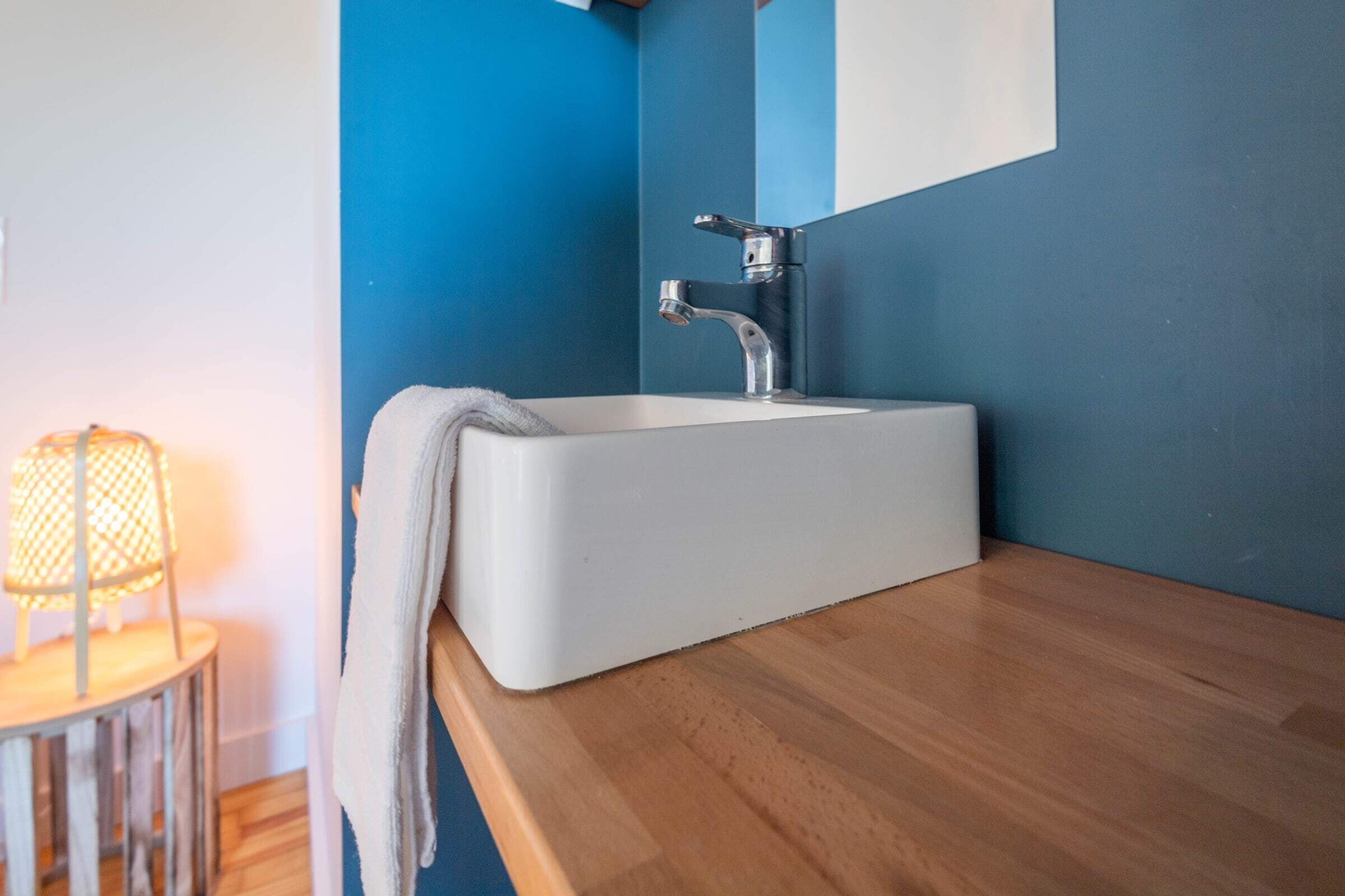 Un baño con un lavamanos blanco, un espejo y una encimera de madera.