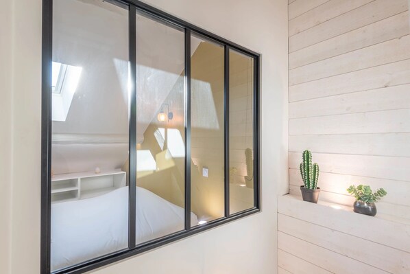 Una habitación con una cama, un ventanal y dos macetas en la pared.