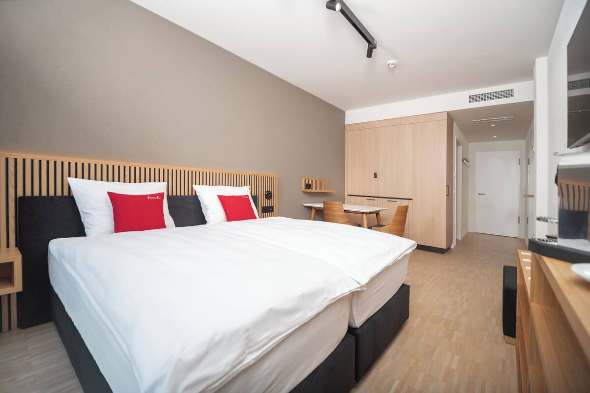 Ein modernes Hotelzimmer mit einem großen Bett, einem Schreibtisch und einem Kleiderschrank.