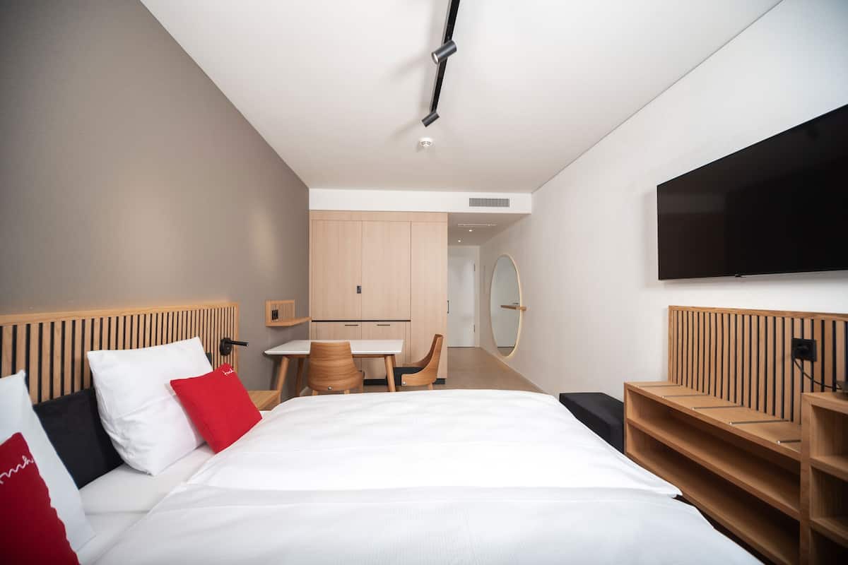 Ein modernes Hotelzimmer mit einem großen Bett, einem Schreibtisch und einem Fernseher.