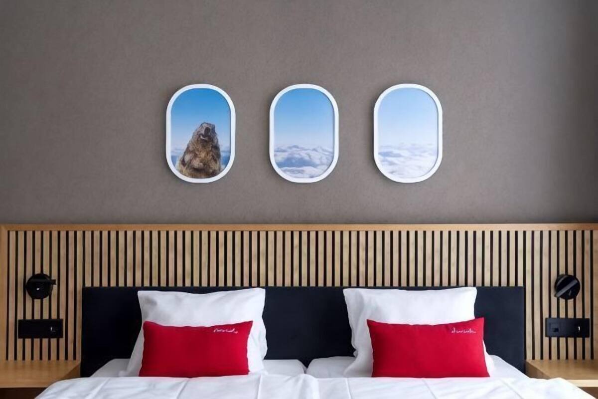 Ein Hotelzimmer mit einem Bett, zwei roten Kissen, einem Holz-Kopfteil und drei gerahmten Bildern an der Wand.