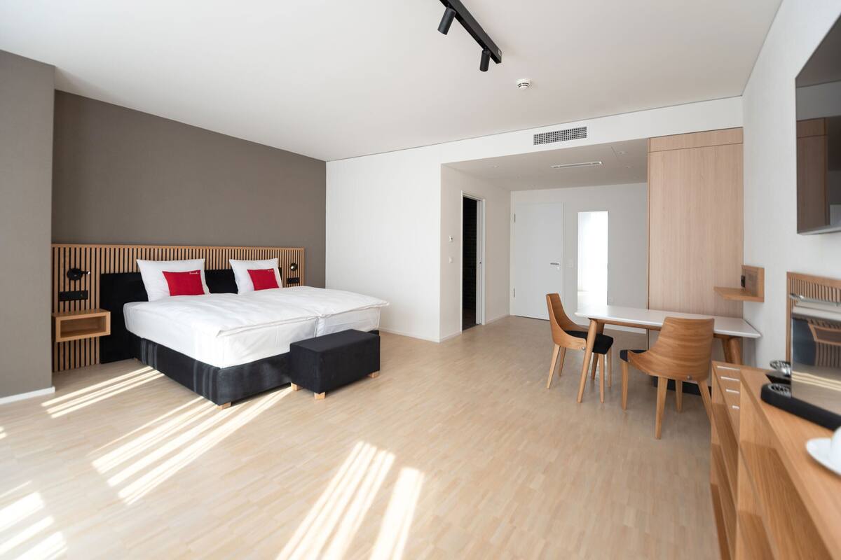 Ein modernes Hotelzimmer mit einem großen Bett, einem Schreibtisch und Stühlen.