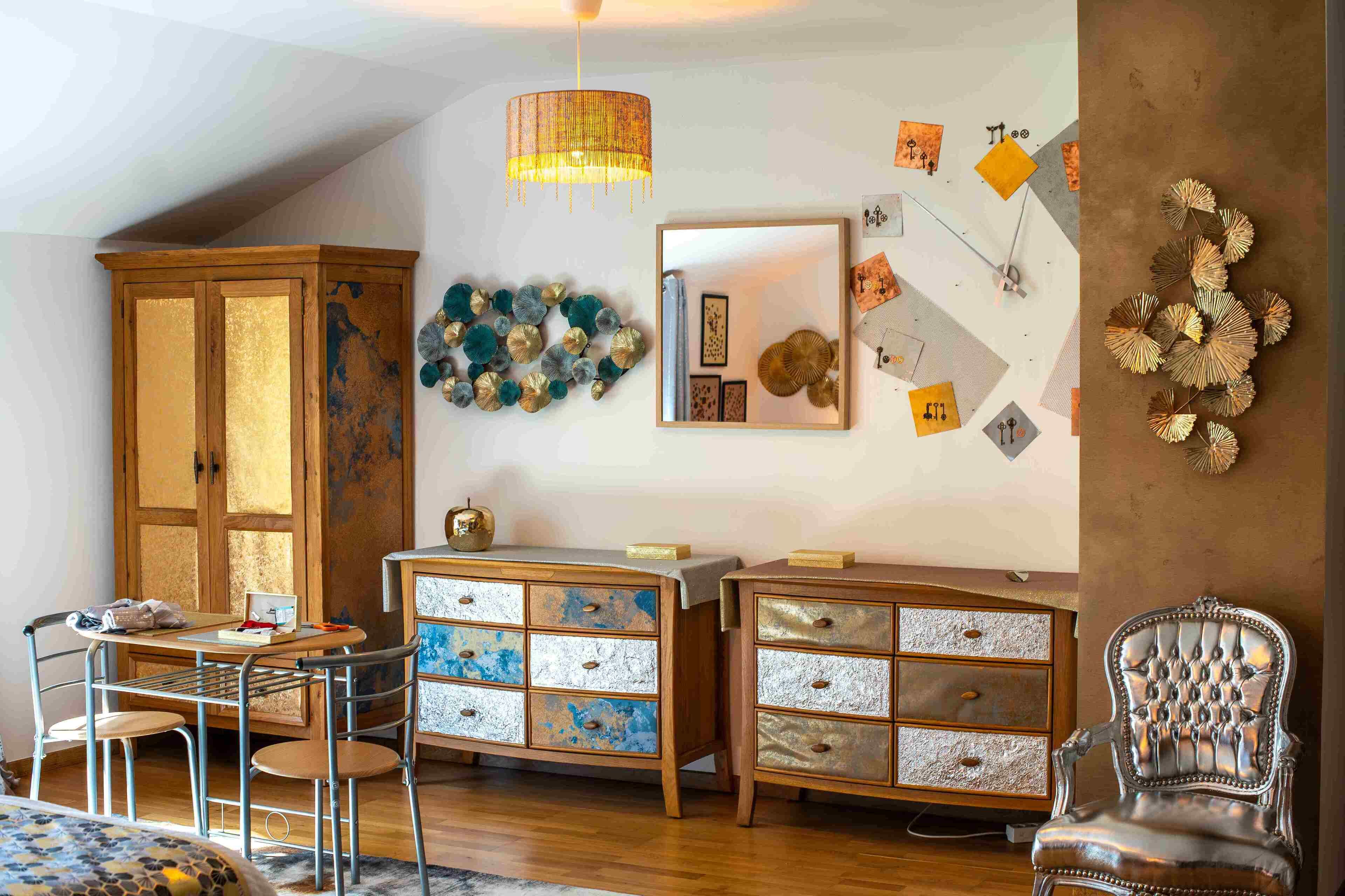 A room with a wooden cabinet, two dressers, a chandelier, and wall decorations.