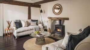 A cozy living room with a fireplace, a round glass coffee table, and a sofa. - Lovely 3-bed House in West Malling, Kent (West Malling)