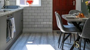 Una cocina moderna con ventana, una mesa de comedor con sillas y una puerta roja.