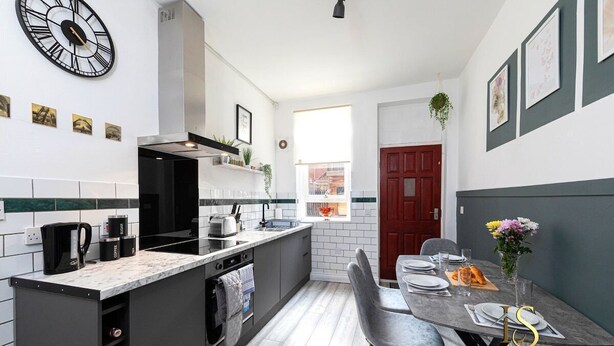 Una cocina moderna con encimera de mármol, horno empotrado y un reloj en la pared.