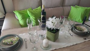 Une table à manger dressée avec des assiettes, des verres, une bouteille de vin et un vase de fleurs.