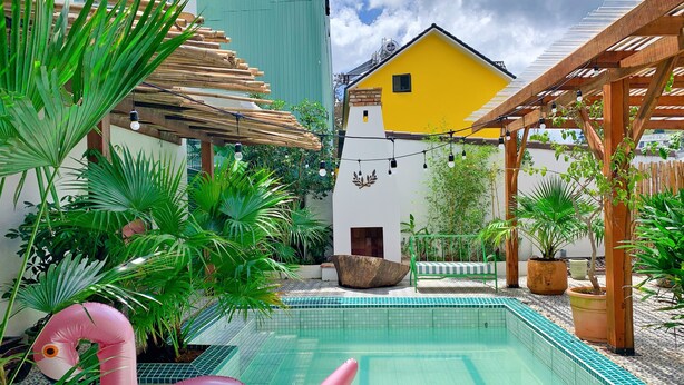 A pool area with a wooden pergola, potted plants, and a pink flamingo float. - Da Lat Lacasa (Xuan Huong - Da Lat)