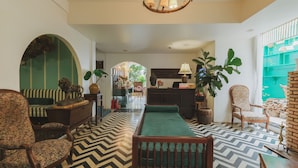 A spacious lobby with a chevron-patterned floor, a green sofa, a wooden bench, and a patterned armchair. - Da Lat Lacasa (Xuan Huong - Da Lat)