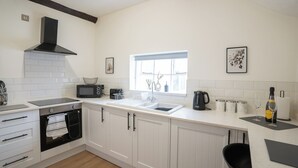 Una cocina moderna con armarios blancos, una campana extractora negra, microondas, lavaplatos y una ventana con vistas.