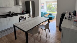 A modern kitchen with a dining area, wooden flooring, and a view of the outdoors.