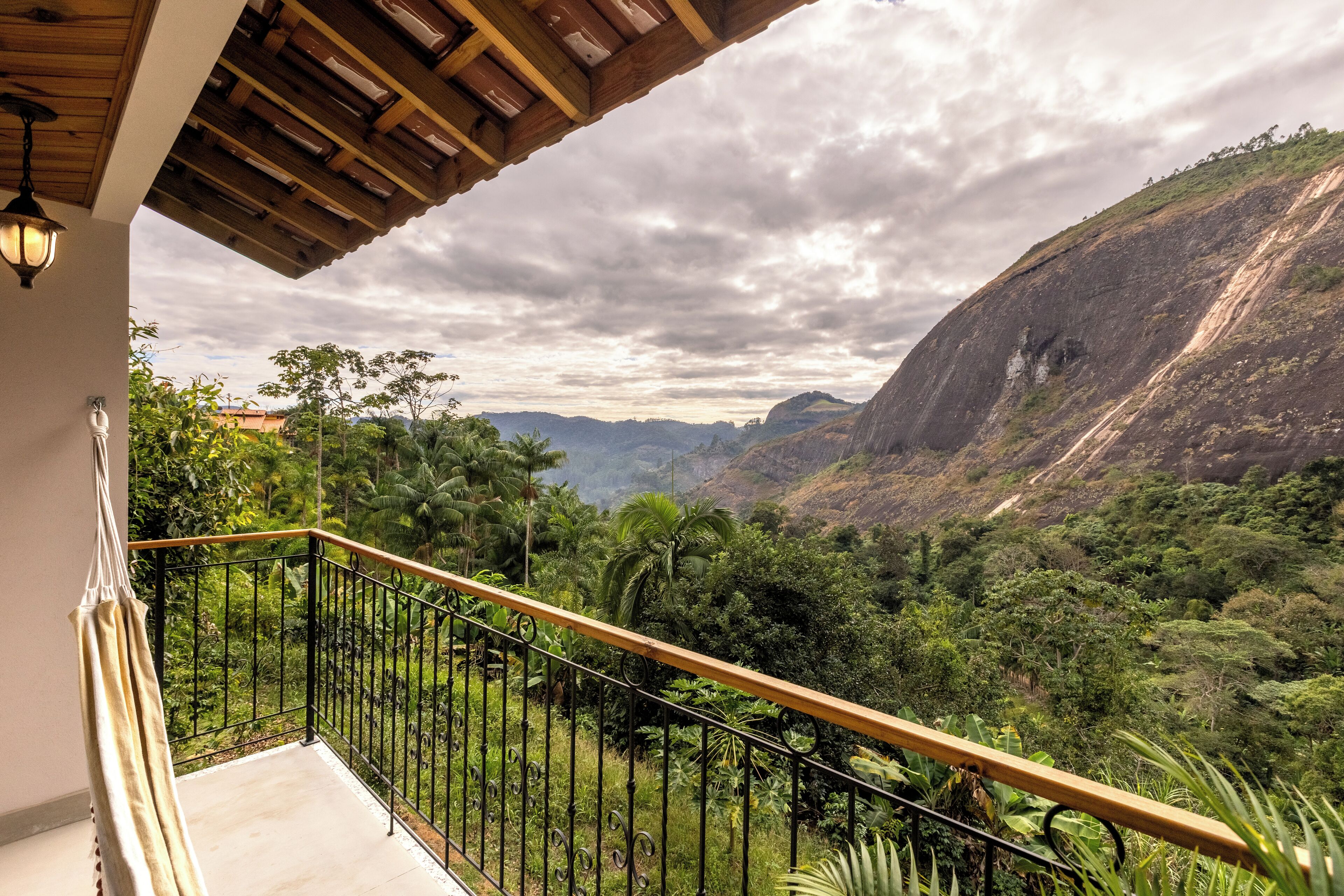 Un balcón con vistas a un valle exuberante y montañas.