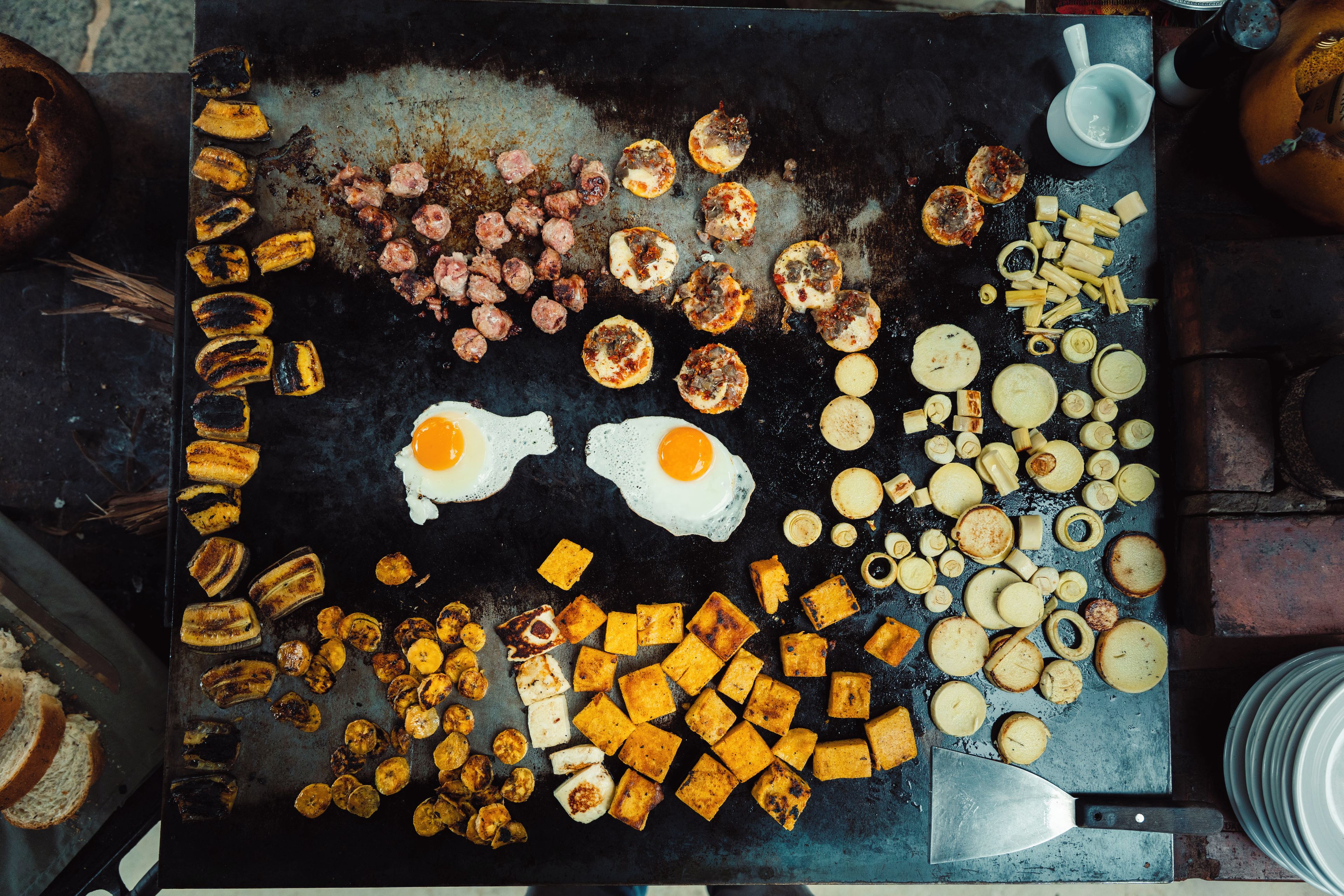 A variety of breakfast items including eggs, bacon, and toast on a griddle.