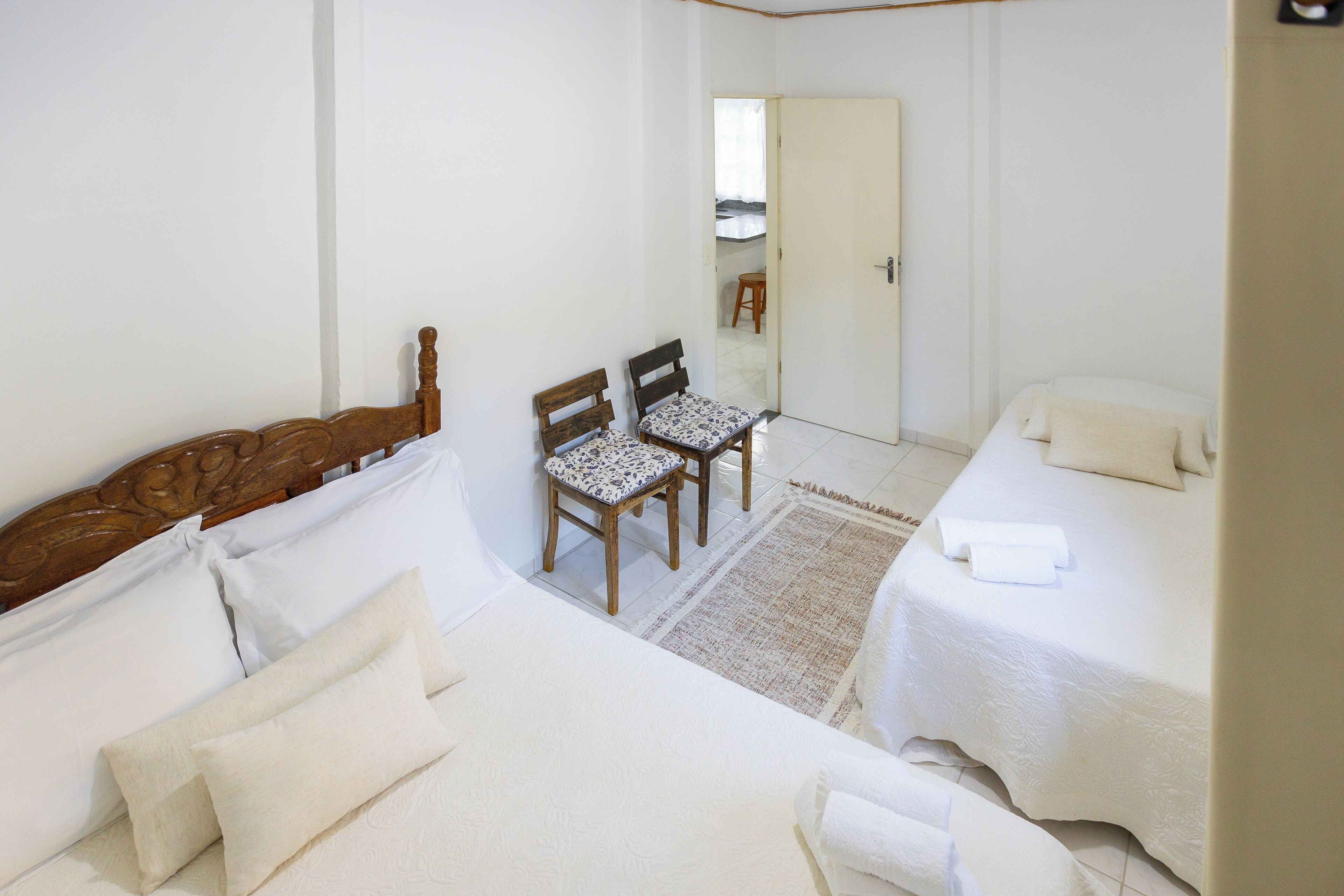A bedroom with two beds, a wooden headboard, a small table with chairs, and a mirror.