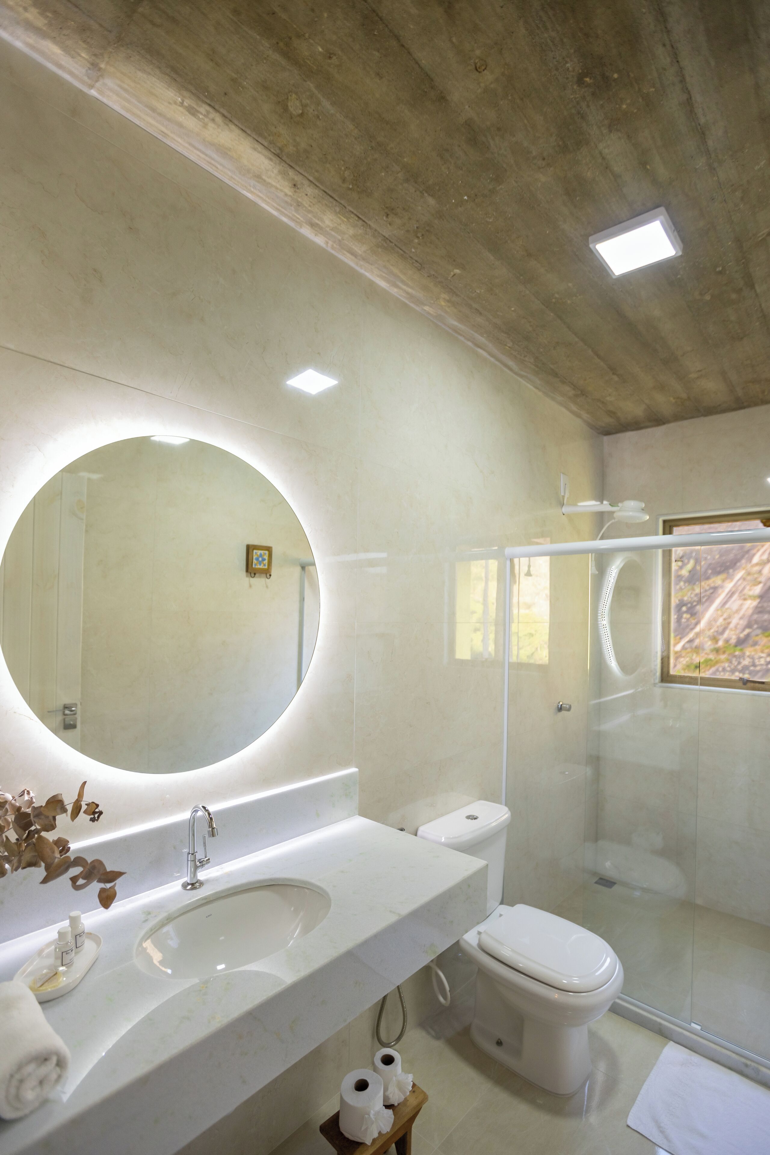 A modern bathroom with a large mirror, a sink, a toilet, and a glass shower enclosure.