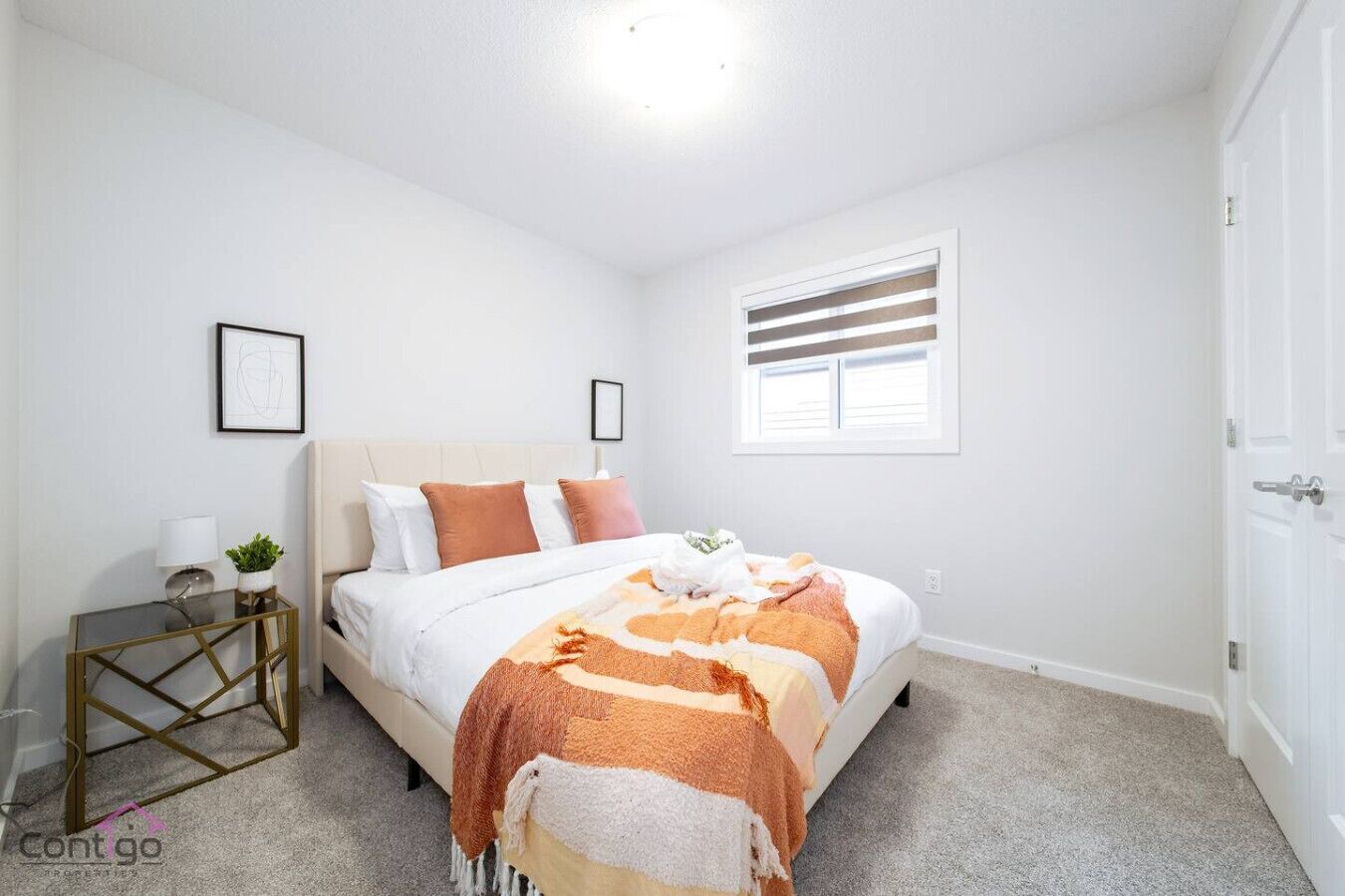A bedroom with a bed, bedside table, lamp, and window.