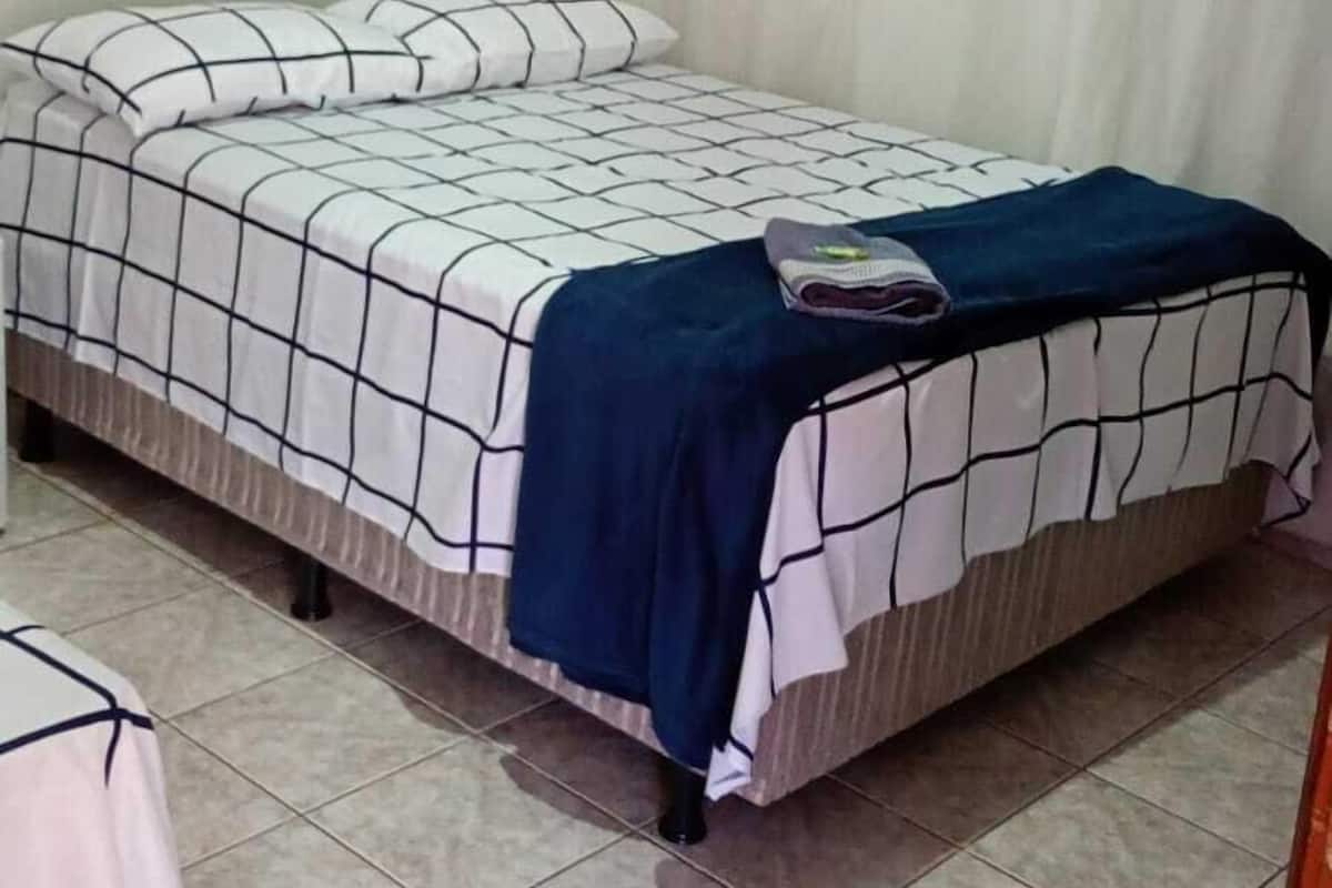 A bedroom with a bed, curtains, and a ceiling fan.