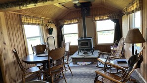 A cozy cabin interior with wooden walls, a stone fireplace, and rustic furniture. - Marzullo's Mountaintop Cabin (Brookville)