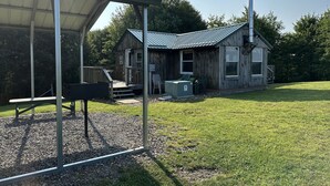 A rustic wooden cabin with a metal roof, a covered patio area, and a grassy yard. - Marzullo's Mountaintop Cabin (Brookville)
